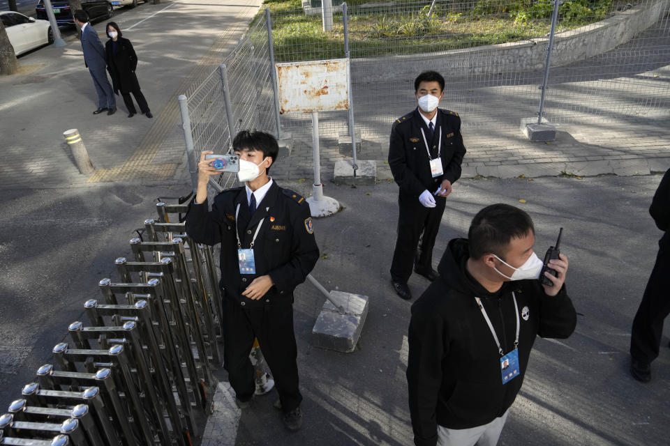 A security official takes a photo of a bus carrying journalists as they leave to cover the closing ceremony of the 20th National Congress of China's ruling Communist Party in Beijing, Saturday, Oct. 22, 2022. (AP Photo/Ng Han Guan)