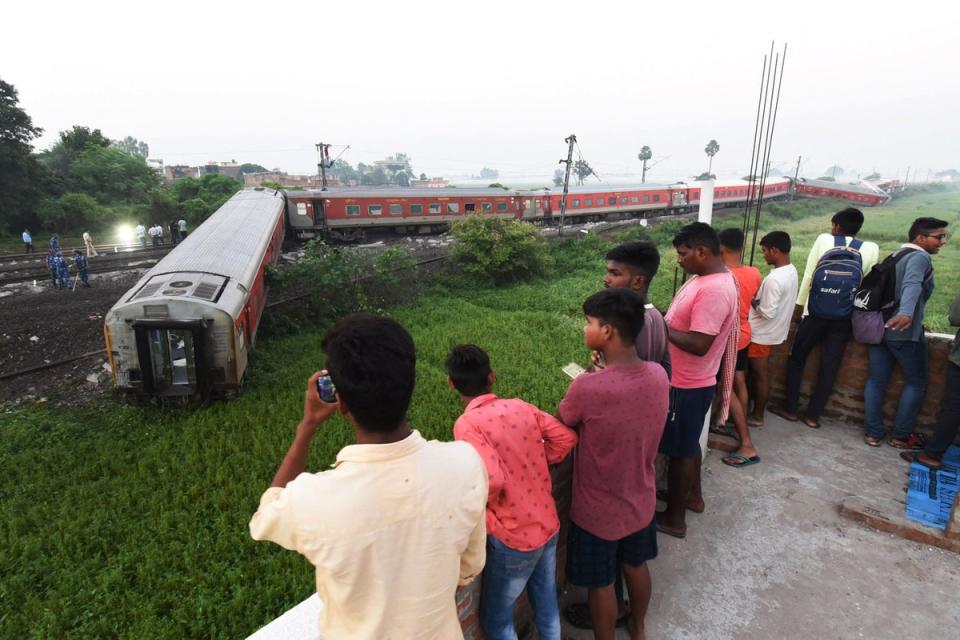 People watch damaged carriages near Raghunathpur railway station some 44km from Buxar on 11 October (AFP via Getty Images)