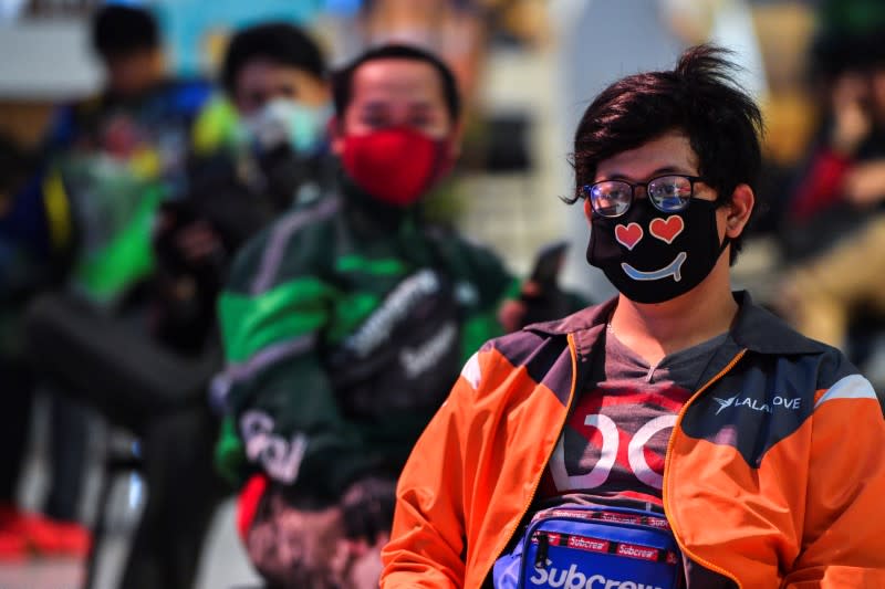 Staff of food delivery service companies, wearing protective face masks due to coronavirus disease (COVID-19) outbreak, wait for their customers' orders at a department store in Bangkok