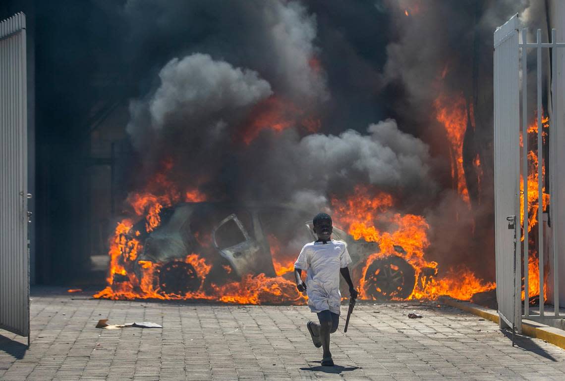 A boy runs out from the Nissan auto dealership set ablaze during a protest in Port-au-Prince, Haiti, Wednesday, March 17, 2021. The protests started when officers and police academy cadets marched toward police headquarters to demand that the bodies of several officers killed during a raid last week on the Village of God shantytown be recovered from the gang still holding them.