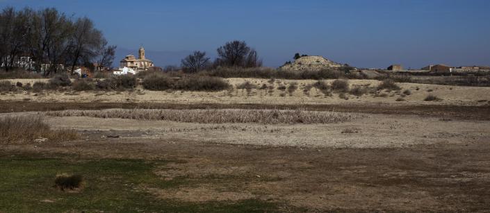 The church of "Nuestra Senyora de la Asuncion" is seen at the background near a dry pool in Robres village, Huesca, Spain, Tuesday March 13, 2012. Spain is suffering the driest winter in more than 70 years, adding yet another woe for an economically distressed country that can scarcely afford it. Thousands of jobs and many millions of euros could be in jeopardy. (AP Photo/Emilio Morenatti)