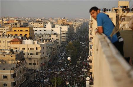 Palestinians gather around Hamas militants as they take part in a military parade marking the first anniversary of the eight-day conflict with Israel, in Gaza City November 14, 2013. REUTERS/Mohammed Salem