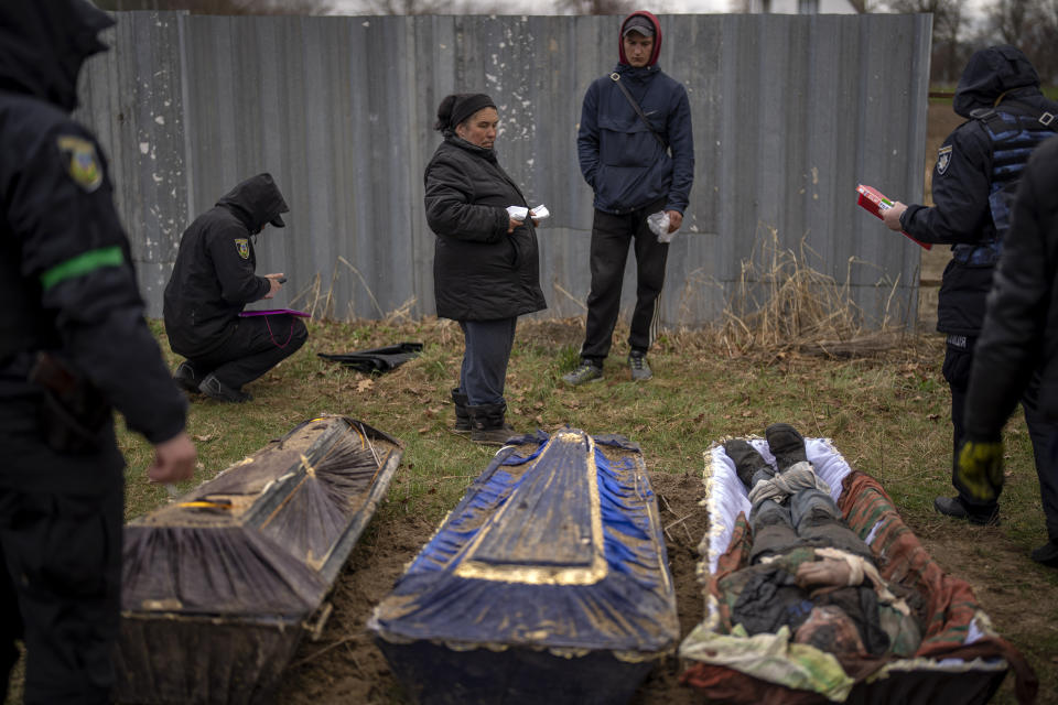 CAPTION CORRECTS LOCATION - Valya Naumenko, 47, identifies the body of her husband Pavlo Ivanyuk, 57, killed by Russian Army, during an exhumation of four civilians killed and buried in a mass grave in Mykulychi, Ukraine on Sunday, April 17, 2022. All four bodies in the village grave were killed on the same street, on the same day. Their temporary caskets were together in a grave. On Sunday, two weeks after the soldiers disappeared, volunteers dug them up one by one to be taken to a morgue for investigation. (AP Photo/Emilio Morenatti)