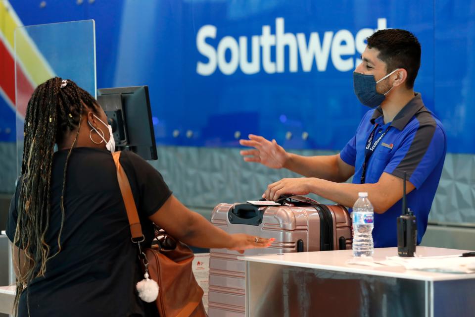 Southwest Airlines employee Oscar Gonzalez, right, assists a passenger at the ticket counter at Love Field in Dallas.