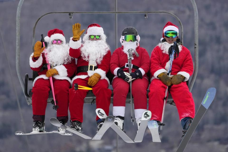 Skiers dressed in Santa Claus outfits ride a chairlift at Sunday River on Dec. 11, 2022.