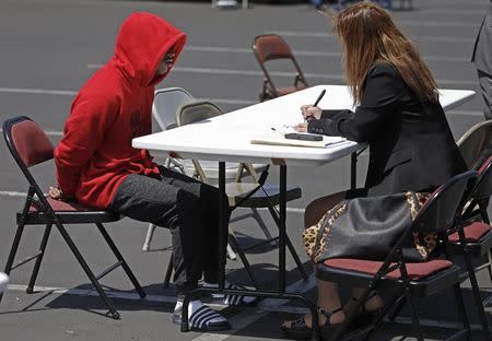 A suspected member of the Broadway Gangster Crips street gang sits while being interviewed by a law enforcement officer after he was arrested in Los Angeles, California June 17, 2014. REUTERS/Jonathan Alcorn