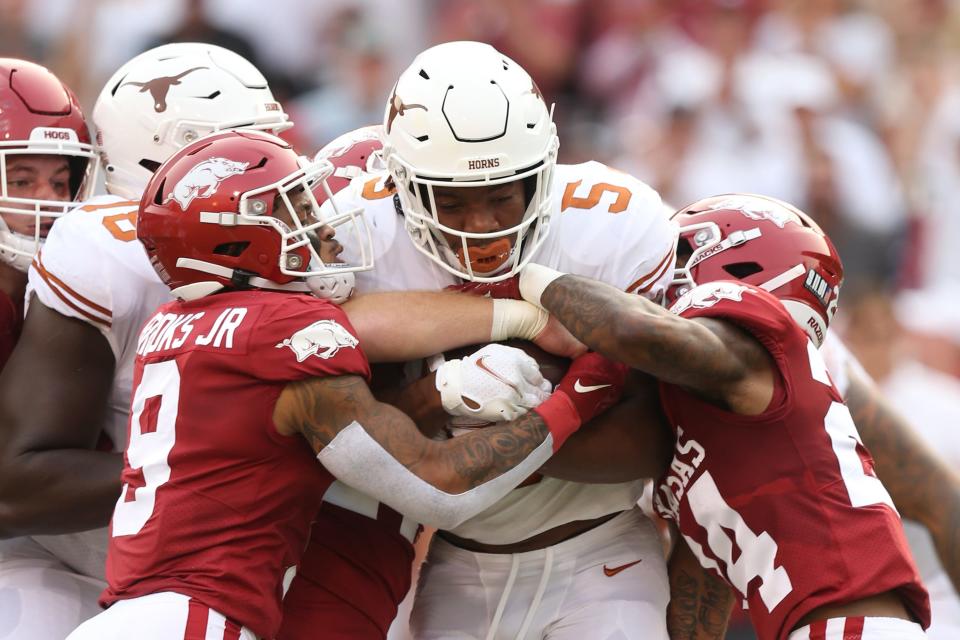 Sep 11, 2021; Fayetteville, Arkansas, USA; Texas Longhorns running back Bijan Robinson (5) is tackled by Arkansas Razorbacks defensive backs Greg Brooks Jr. (9) and LaDarrius Bishop (24) during the first quarter at Donald W. Reynolds Razorback Stadium.