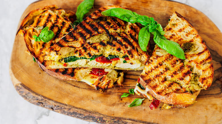 three chicken panini sandwiches on a cutting board