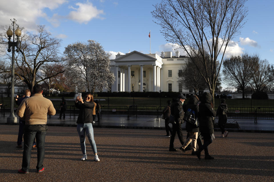 Tourists stand on Pennsylvania Avenue by the White House at sunset, Friday March 22, 2019, in Washington, after the news that special counsel Robert Mueller has concluded his investigation into Russian election interference and possible coordination with associates of President Donald Trump and delivered his final report to Attorney General William Barr. (AP Photo/Jacquelyn Martin)