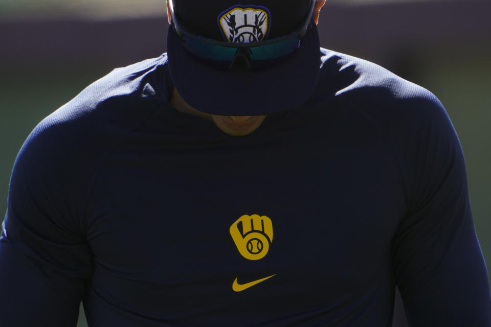 Milwaukee Brewers' Christian Yelich walks past a batting cage during the team's spring training baseball workout in Phoenix, Tuesday, Feb. 23, 2021. (AP Photo/Jae C. Hong)