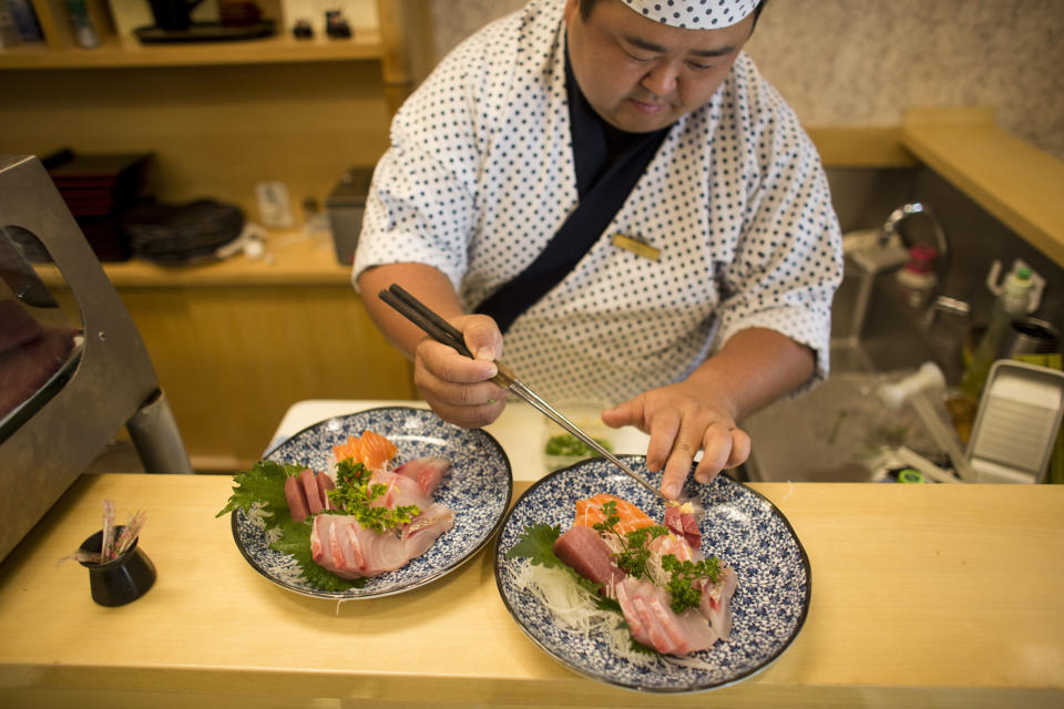 In this Dec. 27, 2018 photo, sushi chef Hiro Konno puts finishing touches on a sashimi plate at the Kenzo restaurant in Sao Paulo's Asian neighborhood of Liberdade, Brazil. "Those of us who have Japanese roots should do more to preserve them. For me, the closing of the newspaper is very sad," said Konno, after the Japanese newspaper Sao Paulo Shimbun ran its last edition, following a 72-year run. (AP Photo/Victor R. Caivano)