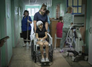 A hospital nurse pushes a wheelchair carrying a woman wounded by the Russian deadly rocket attack at a shopping centre in a city hospital in Kremenchuk in Poltava region, Ukraine, Tuesday, June 28, 2022.(AP Photo/Efrem Lukatsky)