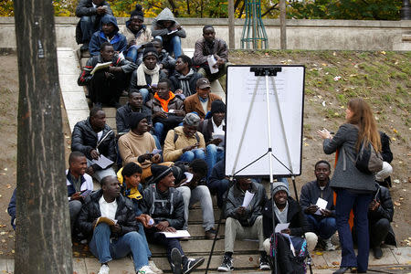 Migrants attend a French lesson near their makeshift camp in Paris, France. REUTERS/Charles Platiau