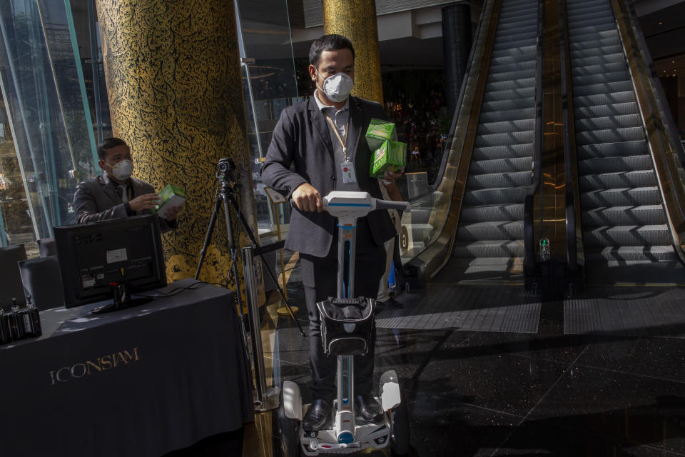 A man on an air-wheel carry protective face masks to be distributed for visitors at a luxury mall in Bangkok, Thailand, Tuesday, Jan. 28, 2020. Panic and pollution drive the market for protective face masks, so business is booming in Asia, where fear of the coronavirus from China is straining supplies and helping make mask-wearing the new normal. (AP Photo/Gemunu Amarasinghe)