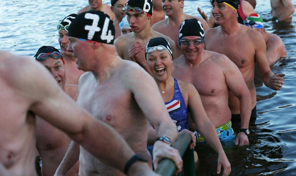 Swimmers emerge from the Serpentine river on Christmas Day in Hyde Park, central London December 25, 2013. For over 100 years, swimmers have taken part in the Christmas Day "Peter Pan" swim in the Serpentine. REUTERS/Suzanne Plunkett (BRITAIN - Tags: SOCIETY SPORT SWIMMING)