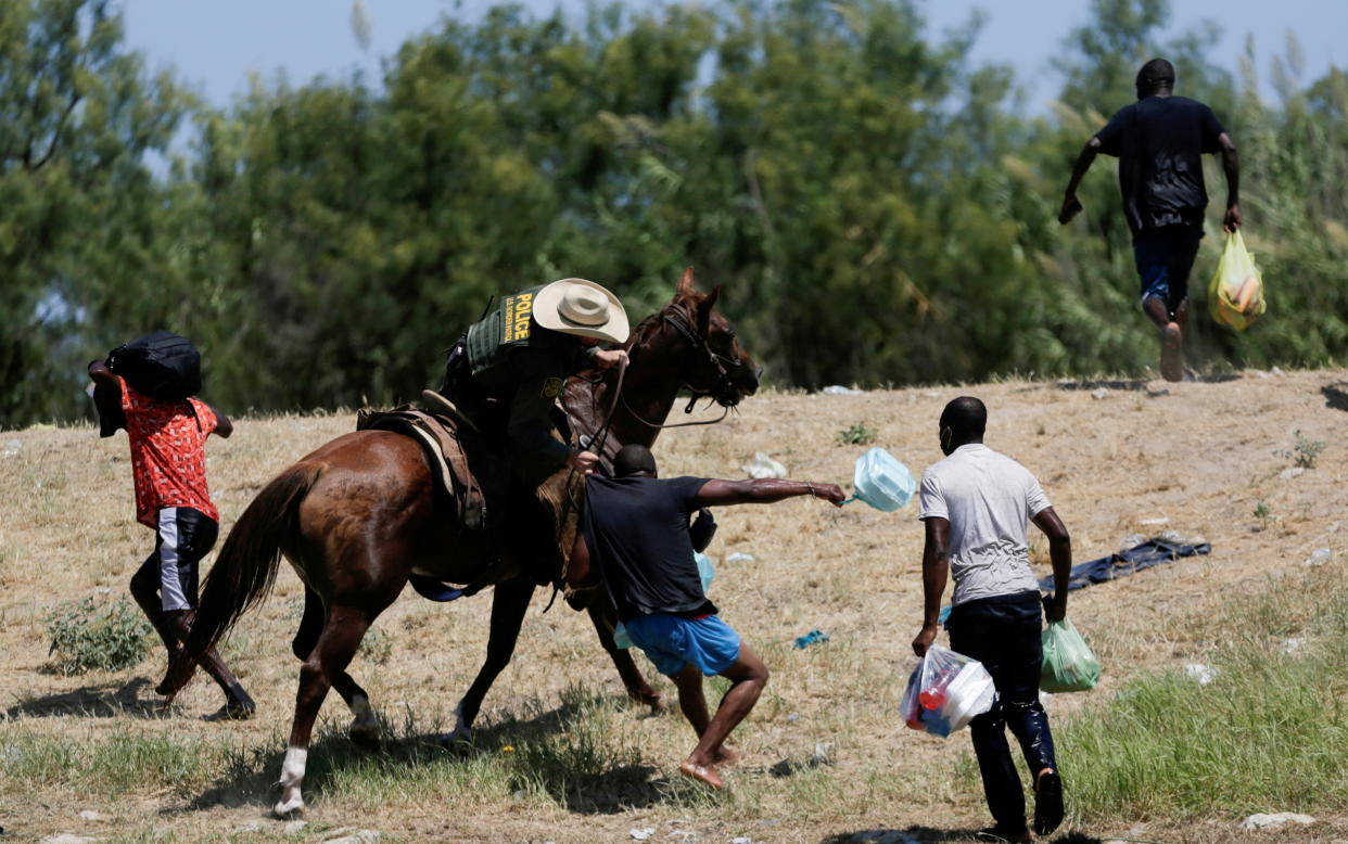 Un agente agarra por la camisa a un migrante haitiano que intenta regresar a EEUU tras cruzar a México por el Río Grande en busca de comida. REUTERS/Daniel Becerril