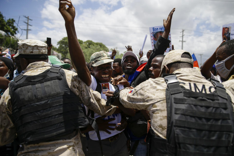 Supporters of former Haitian President Jean-Bertrand Aristide celebrate his arrival from Cuba, where he underwent medical treatment, in Port-au-Prince, Haiti, Friday, July 16, 2021. Aristide's return adds a potentially volatile element to an already tense situation in a country facing a power vacuum following the July 7 assassination of President Jovenel Moïse. (AP Photo/Joseph Odelyn)