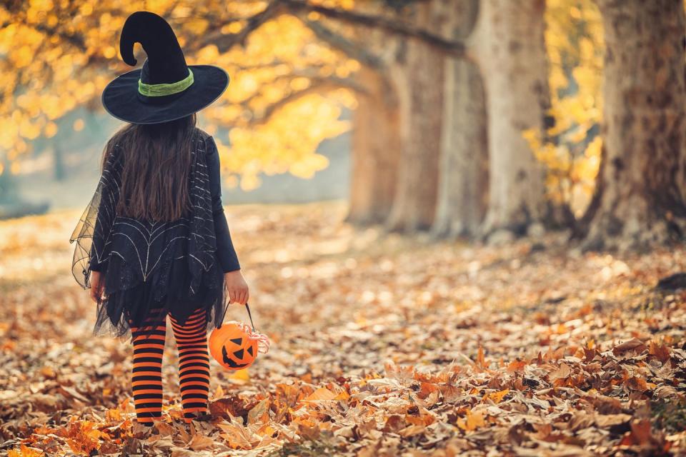 little girl in witch costume having fun outdoors on halloween trick or treat