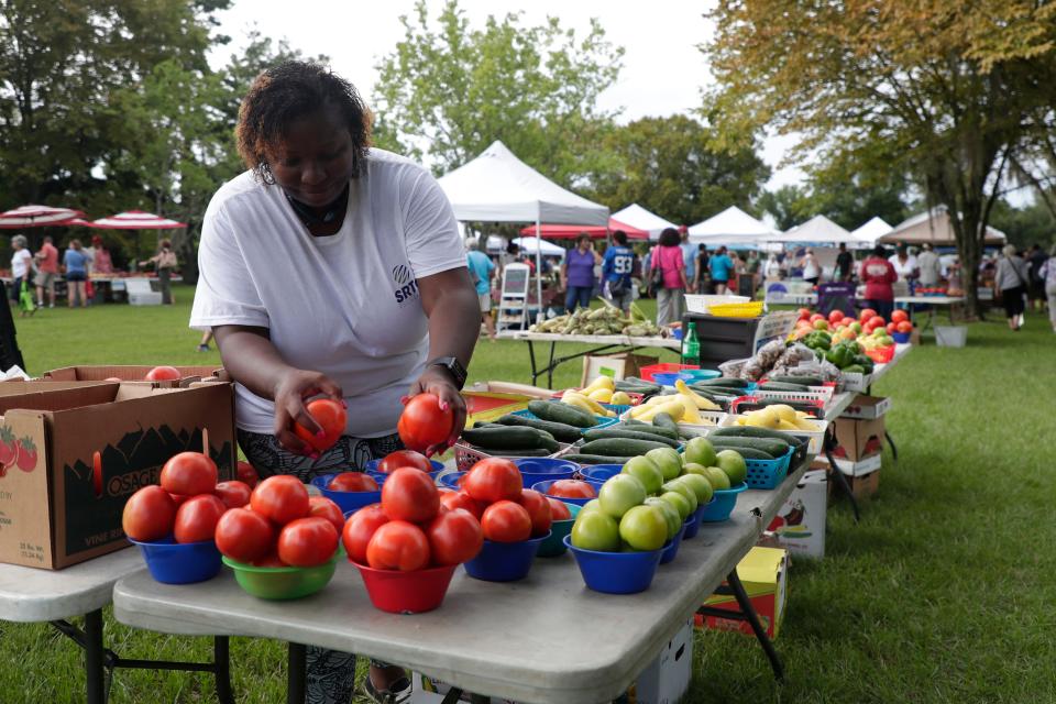 Crystal Holt, who sells fresh produce from Fresh Basket Produce at the Tallahassee Farmers Market, fills up bowls with tomatoes for customers. 