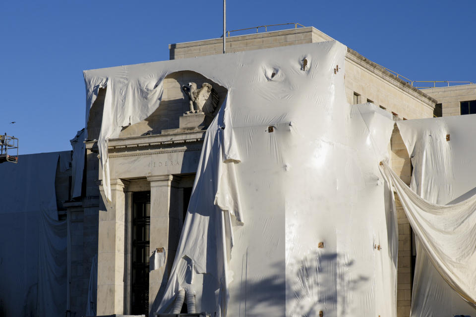 File - The sculpture of an eagle looks out from behind protective construction wrapping on the facade as the Federal Reserve Board Building undergoes both interior and exterior renovations, in Washington, Oct. 23, 2023. The Federal Reserve is expected to leave interest rates alone when its latest meeting ends Wednesday. But economists will be listening closely to what Chair Jerome Powell says about the possible future path for rates. (AP Photo/J. Scott Applewhite, File)