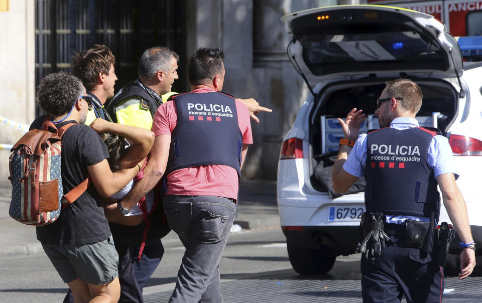 An injured person is carried in Barcelona, Spain, Aug. 17, 2017, after a white van jumped the sidewalk in a historic district, crashing into a summer crowd. (Oriol Duran/AP)