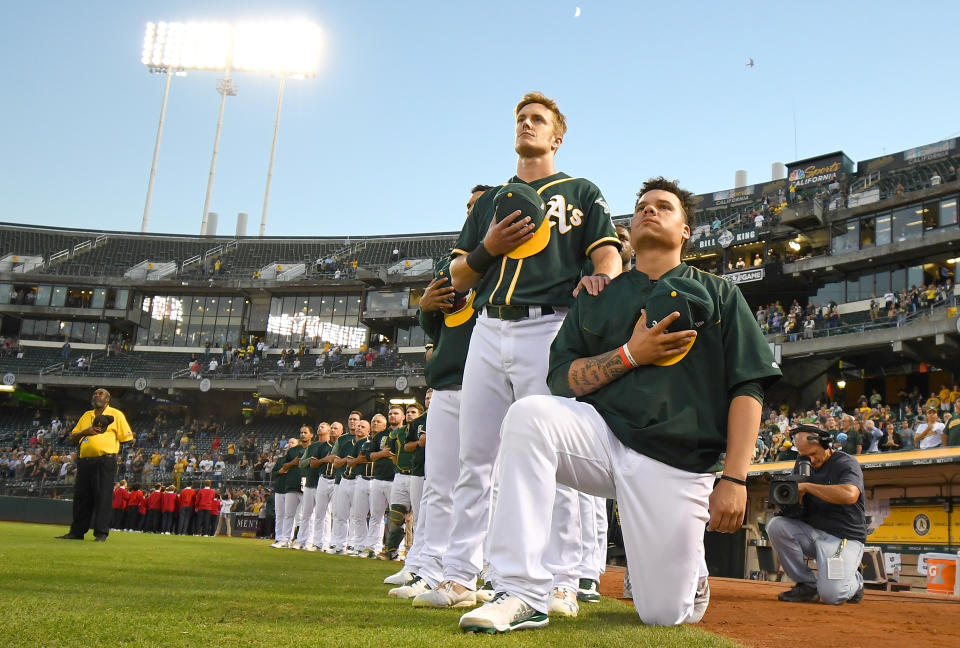 OAKLAND, CA - SEPTEMBER 26:  Bruce Maxwell #13 of the Oakland Athletics kneels in protest next to teammate Mark Canha #20 duing the singing of the National Anthem prior to the start of the game against the Seattle Mariners at Oakland Alameda Coliseum on September 26, 2017 in Oakland, California.  (Photo by Thearon W. Henderson/Getty Images)