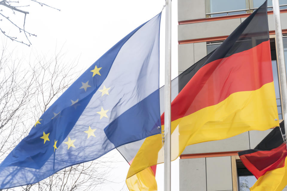 German and European Union flags waving against cloudy sky