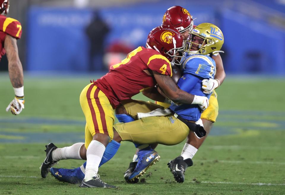 UCS's Max Williams (4) and Tuli Tuipulotu tackle UCLA quarterback Dorian Thompson-Robinson on Dec. 12 at the Rose Bowl.