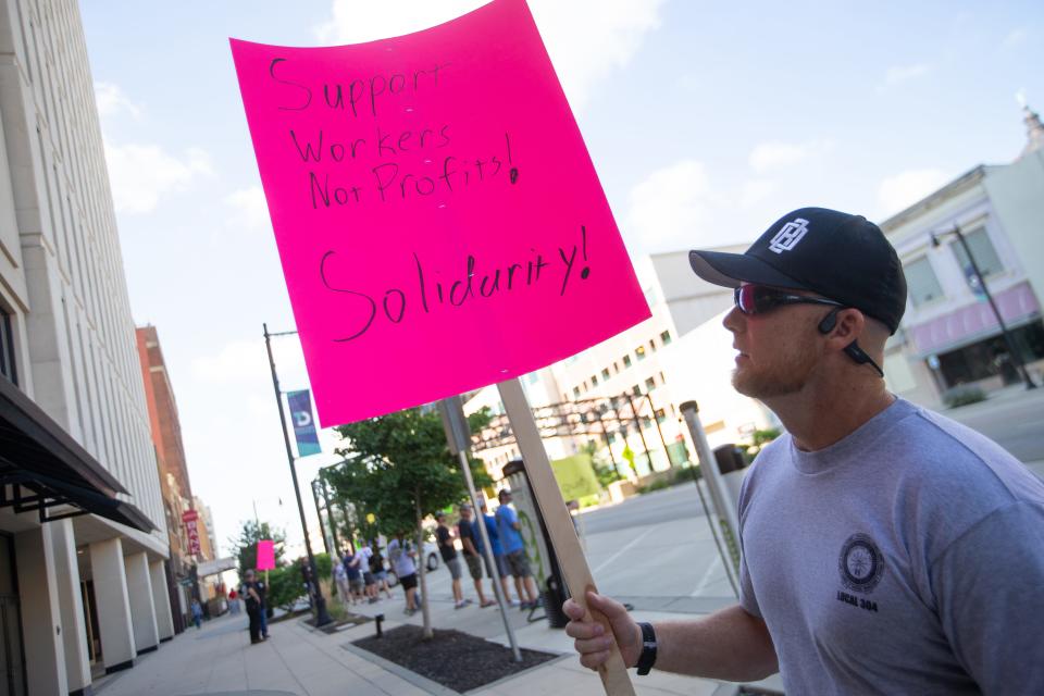 Zac Keeshan, an IBEW Local 304 electrician who works out of the Jeffrey Energy Center, shows his sign asking for support for Evergy union employees Monday during an informational picket in downtown Topeka.