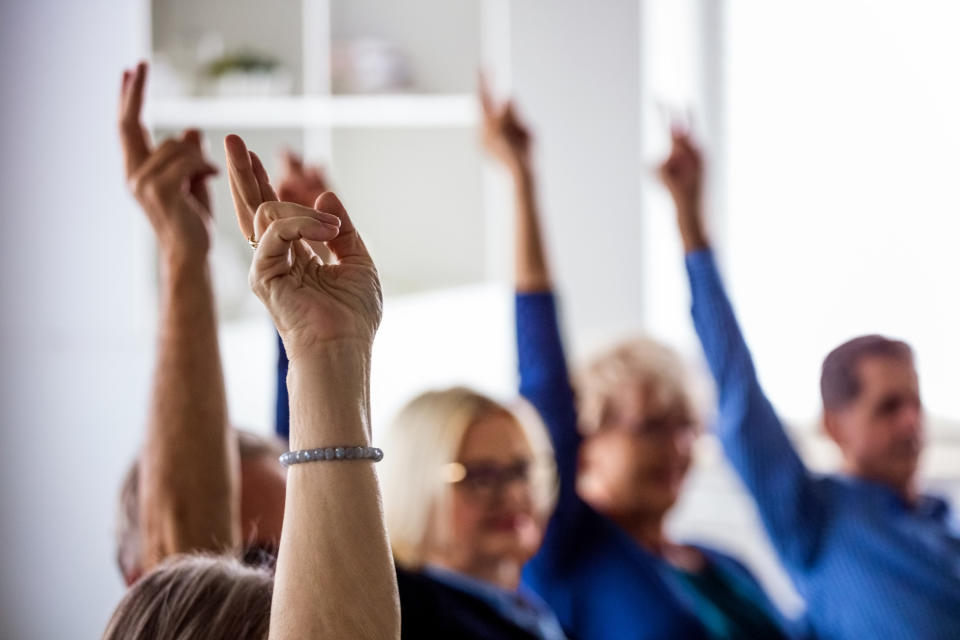 Community members voting in a meeting with raised hands