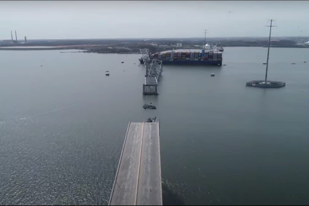 A collapsed bridge with a large vessel seen in the background