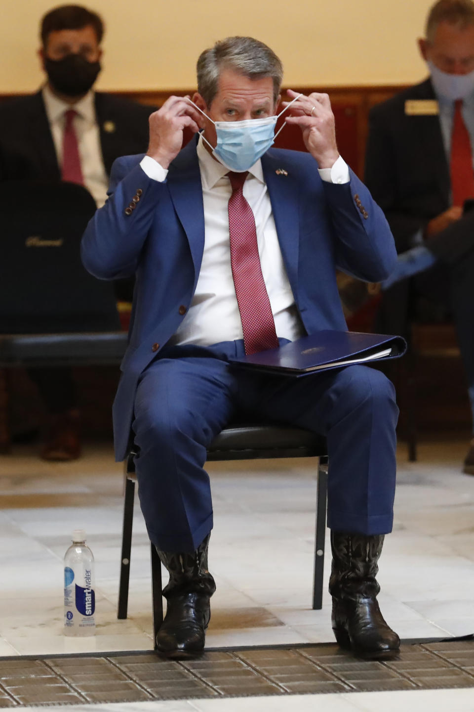 Georgia Gov. Brian Kemp adjusts his face covering as the waits to speak during a coronavirus briefing at the Capitol Friday, July 17, 2020, in Atlanta. Kemp sued the city of Atlanta over its face-mask requirement just after President Donald Trump arrived in the city without wearing a mask, Mayor Keisha Lance Bottoms said Friday. (AP Photo/John Bazemore)