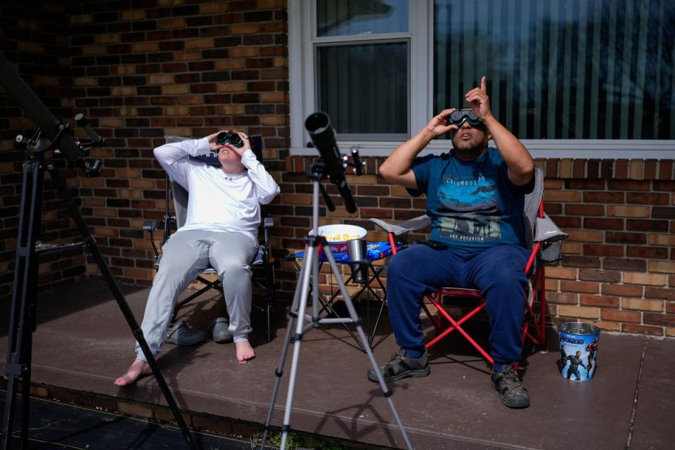 Melissa, left, and Michael Richards watch through solar goggles as the moon partially covers the sun during a total solar eclipse, as seen from Wooster, Ohio.<span class="copyright">solar-eclipse-photos-16</span>