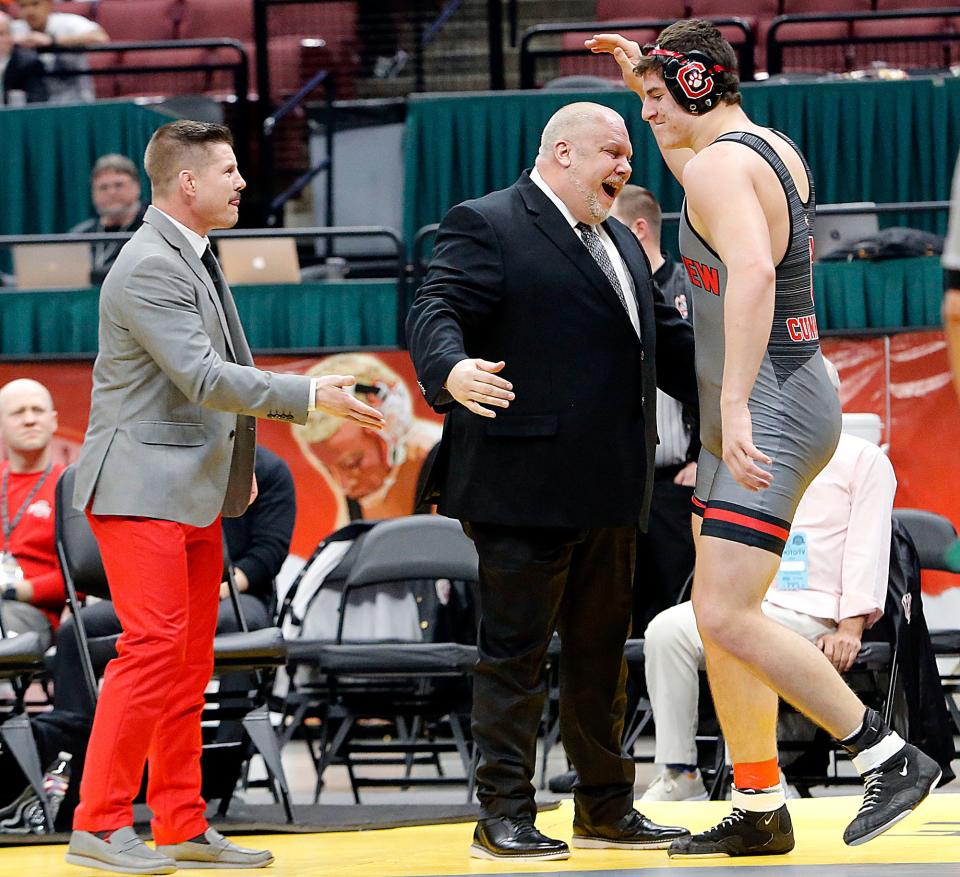 Crestview’s Caleb Cunningham celebrates with head coach Nathan Godsey, left, and coach Steve Haverdill after pinning Harrison Central’s Landen Thomas in the first period during their 285lbs Division III championship match at the OHSAA State Wrestling Championships Sunday, March 10, 2024 at the Jerome Schottenstein Center. TOM E. PUSKAR/MANSFIELD NEWS JOURNAL