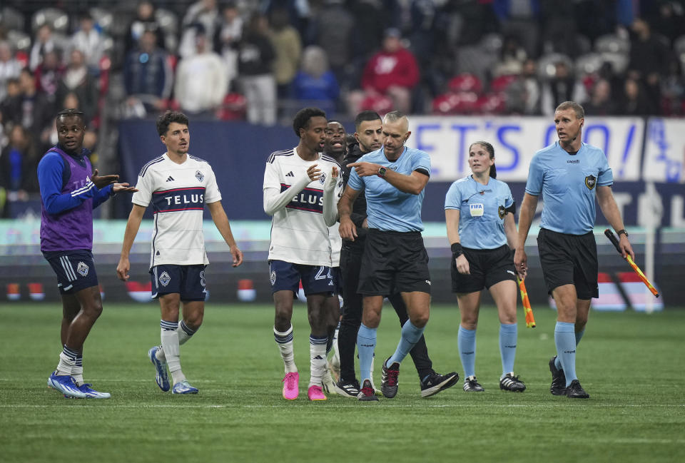 Referee Tim Ford, center right, is followed by Vancouver Whitecaps' Ali Ahmed, center left, and Sam Adekugbe, back left, as he leaves the field after Los Angeles FC defeated the Whitecaps in Game 2 of a first-round MLS playoff soccer match in Vancouver, British Columbia, Sunday, Nov. 5, 2023. (Darryl Dyck/The Canadian Press via AP)