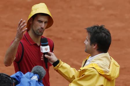 Tennis - French Open - Roland Garros - Novak Djokovic of Serbia v Roberto Bautista Agut of Spain - Paris, France - 1/06/16. Novak Djokovic wears a rain hat as he answers to former French tennis player Arnaud Clement. REUTERS/Pascal Rossignol