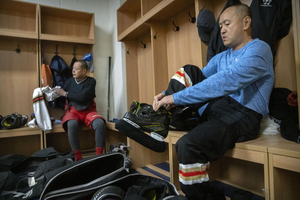 Members of the "1979" hockey club put on their gear in the locker room before a match at a hockey rink in Beijing, Wednesday, Jan. 12, 2022. Spurred by enthusiasm after China was awarded the 2022 Winter Olympics, the members of a 1970s-era youth hockey team, now around 60 years old, have reunited decades later to once again take to the ice. (AP Photo/Mark Schiefelbein)