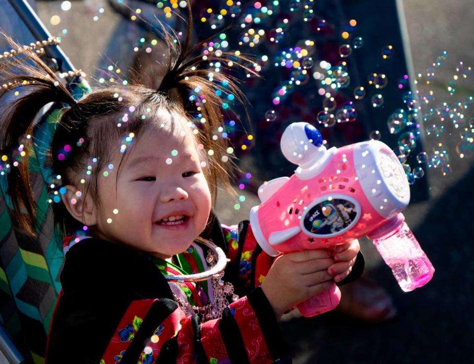 Heart Vue, 2, of Sacramento, plays with a new bubble gun she got as thousands celebrate the Sacramento Hmong New Year festival Saturday.