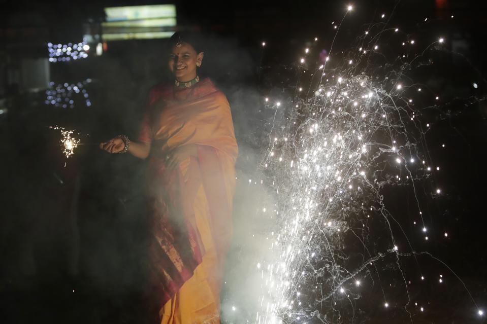 A woman celebrates Diwali at Shivaji park in Mumbai, India, Thursday, Nov. 4, 2021. Diwali, the festival of lights, is one of Hinduism's most important festivals dedicated to the worship of Lakshmi, the Hindu goddess of wealth. (AP Photo/Rajanish kakade)