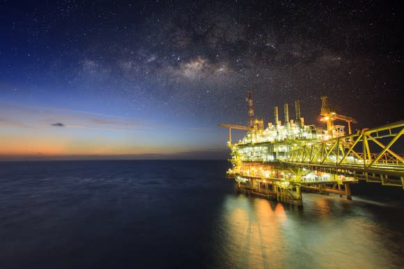 An offshore oil rig with its lights on in open water