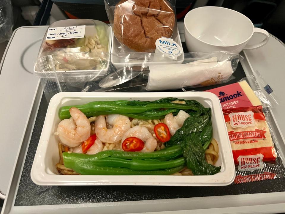 Singapore Airlines’ dinner meal in premium economy, including prawns with leaks and noodles, orzo, bread, cheese, and crackers.