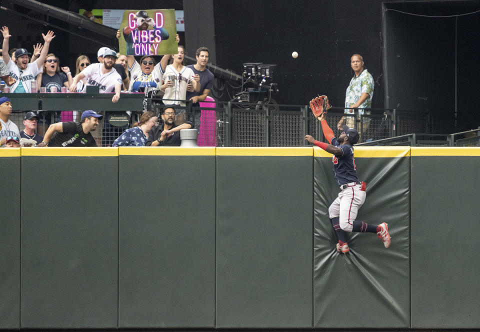 Atlanta Braves centerfielder Michael Harris II climbs the outfield wall in an attempt to get to a home run ball hit by Seattle Mariners' Eugenio Suarez during the fifth inning of a baseball game, Sunday, Sept. 11, 2022, in Seattle. (AP Photo/Stephen Brashear)