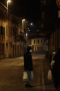 People wearing sanitary mask and carrying some goods they shopped for, stop by a cash machine in the center of Codogno, near Lodi, Northern Italy, Saturday, Feb. 22, 2020. A dozen northern Italian towns were on effective lockdown Saturday after the new virus linked to China claimed two fatalities in Italy and sickened an increasing number of people who had no direct links to the origin of the virus. The secondary contagions prompted local authorities in towns in Lombardy and Veneto to order schools, businesses and restaurants closed, and to cancel sporting events and Masses. (AP Photo/Luca Bruno)