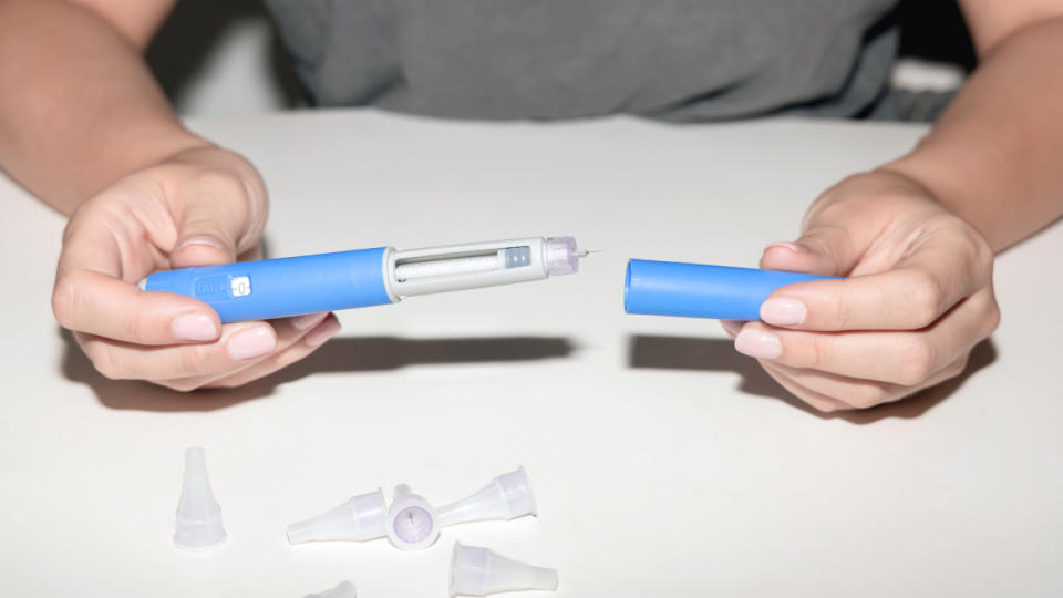 A close-up of a woman's hand holding Ozempic injectable pen