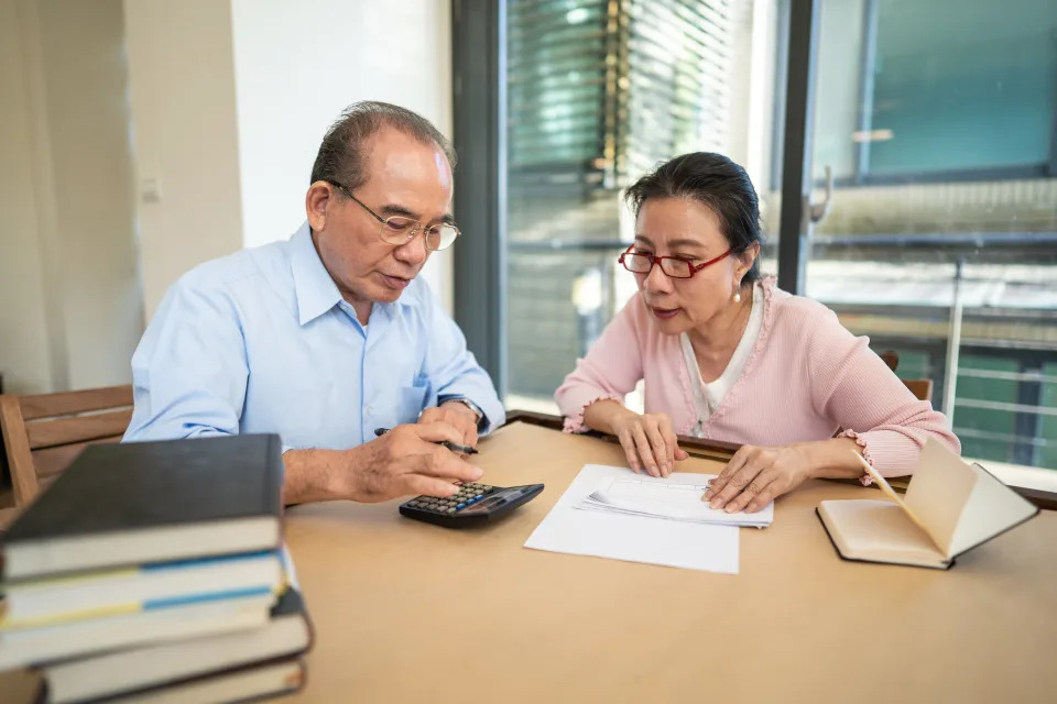Taiwanese, senior, married couple sitting in dining room at home and calculating their home finances