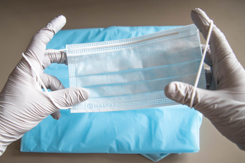 A health care worker holds a surgery mask.