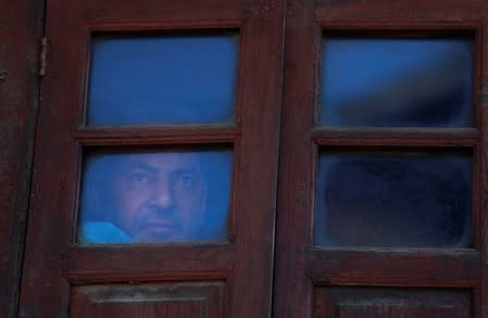 A man looks out from a window of his house during restrictions, in Srinagar