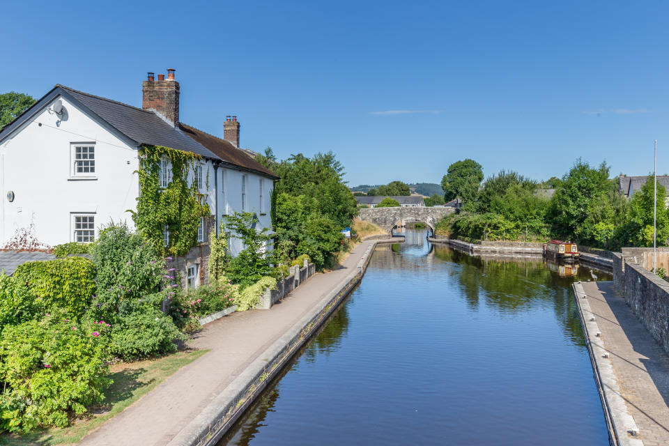 Cottages, bridge and barge  reflecting in the water of  Brecon Canal basin  in Brecon town, Brecon Beacons National Park, Wales, UK