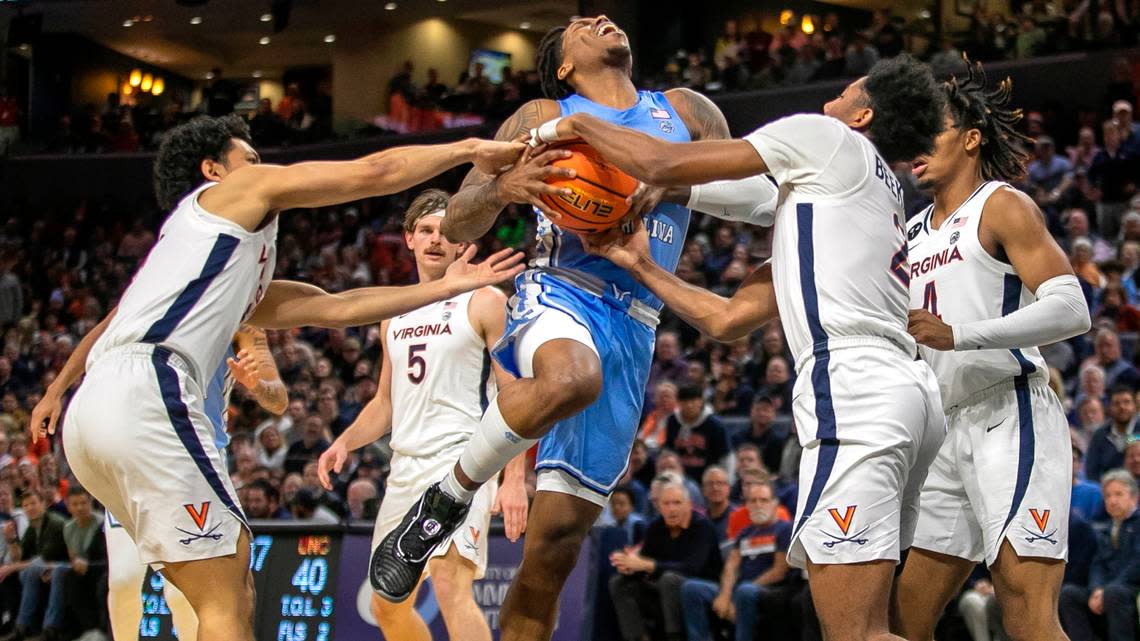 Virginia’s Kihei Clark (0) and Reece Beekman (2) stops North Carolina’s Caleb Love (2) as he drives to the basket in the second half on Tuesday, January 10, 2023 at John Paul Jones Arena in Charlottesville, Va. Virginia defeated North Carolina 65-58.