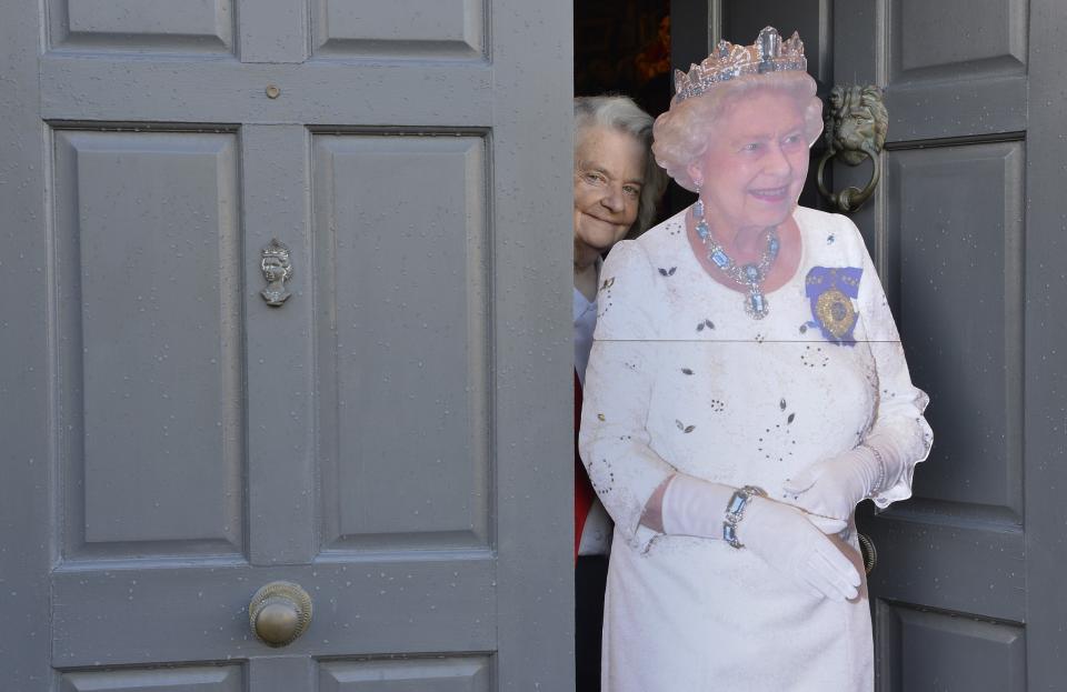 Margaret Tyler poses next to a cutout life-size figure of Britain's Queen Elizabeth at the front door of her house in west London